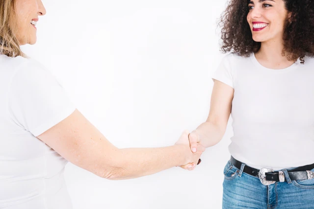 Zwei Frauen geben sich lächelnd die Hand
