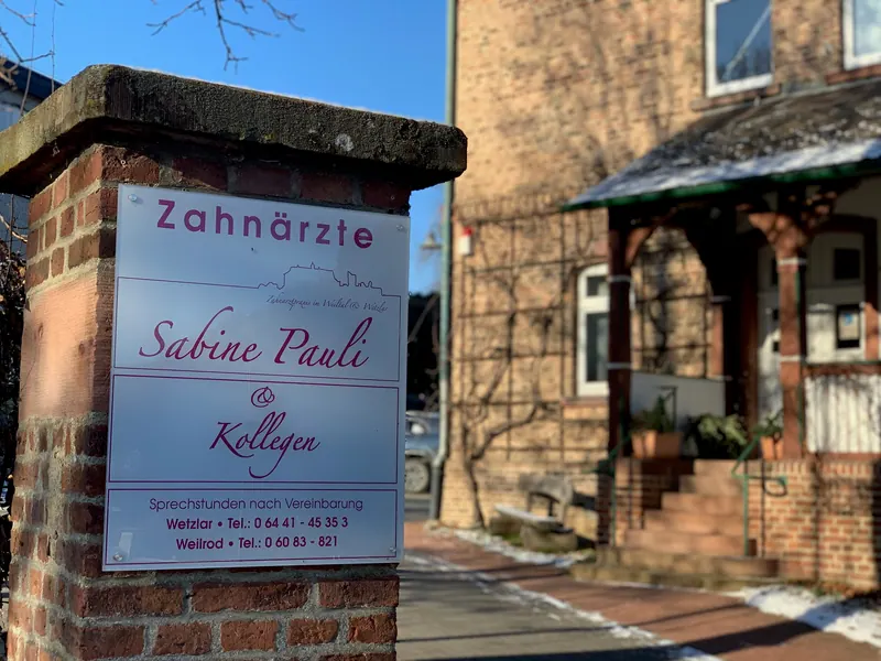 Praxisschild „Zahnärzte Sabine Pauli & Kollegen“ vor dem Backsteinhaus in der Weilstraße